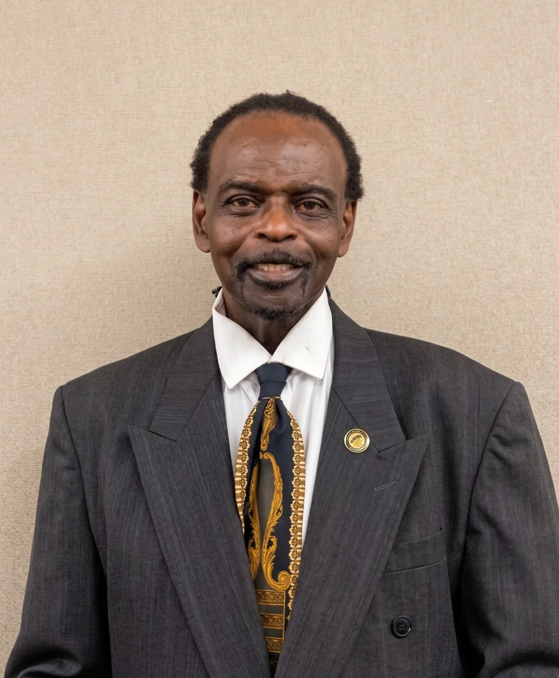 Dr. Ameni Alexander in a charcoal suit with a black and gold tie